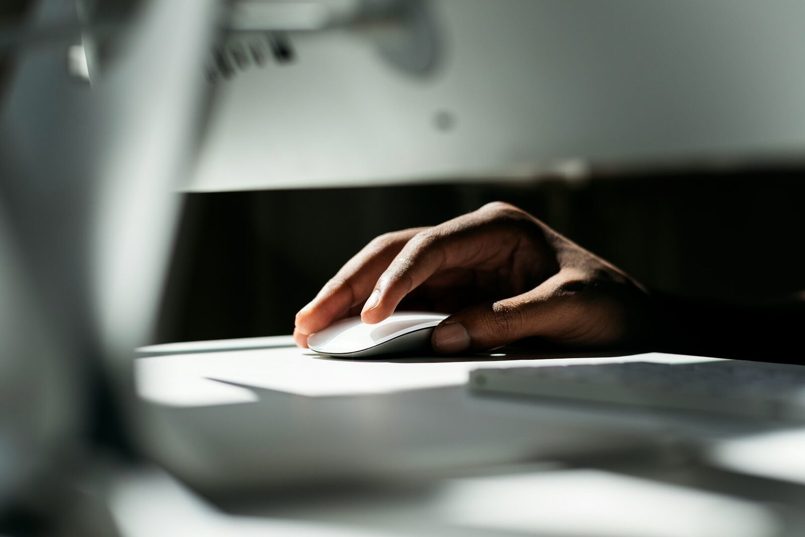 Hand resting on a white Magic Mouse beside a keyboard, illustrating cursor-driven hover states and micro-interactions in web design
