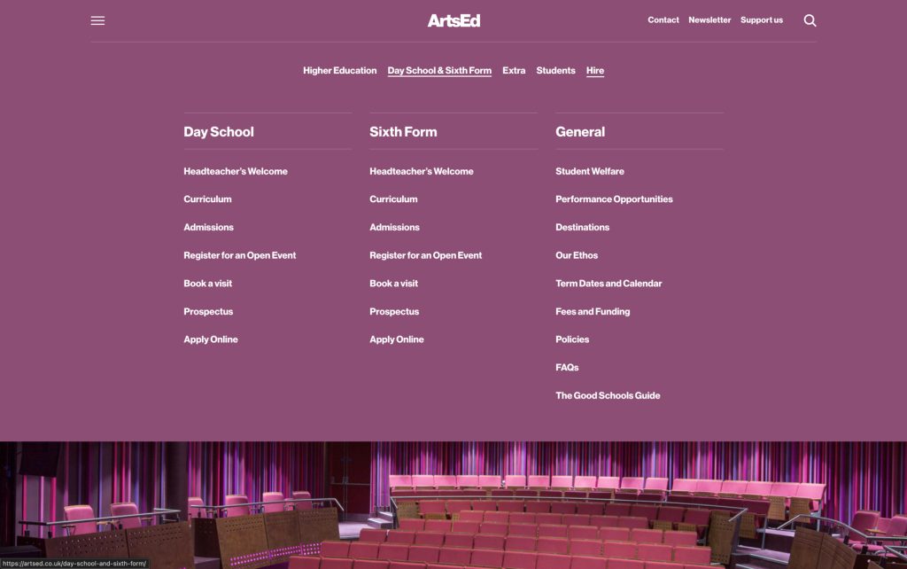 Empty auditorium with pink seats and stage, ready for a performance or event.